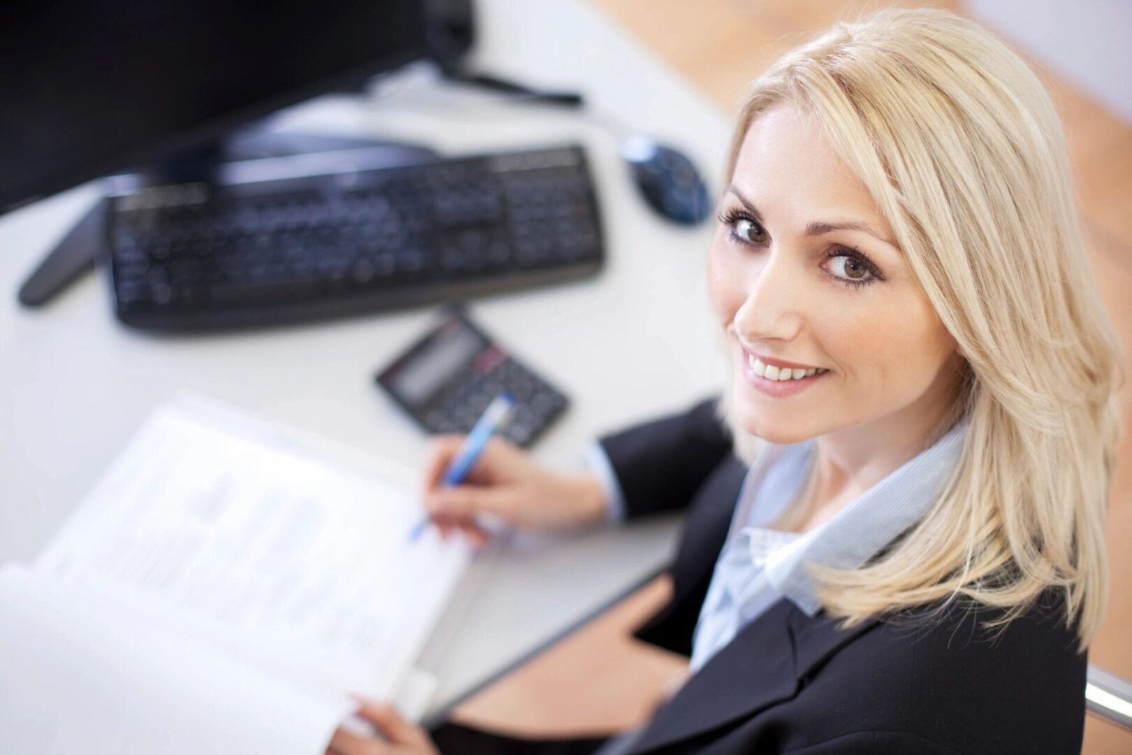 A woman sitting at her desk with papers and calculator.