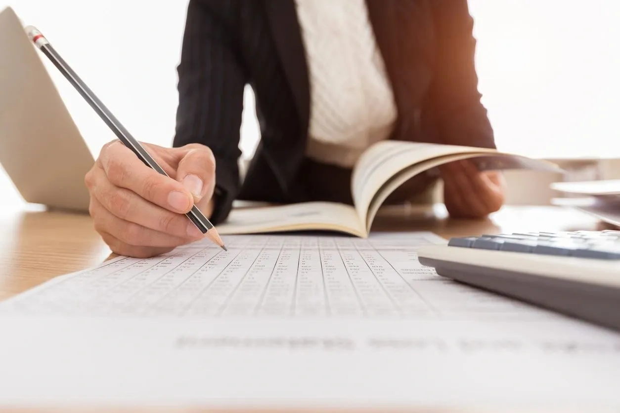 A person writing on a book with a pencil